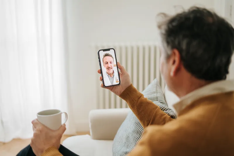 An older man at home on a video call with his health advisor.