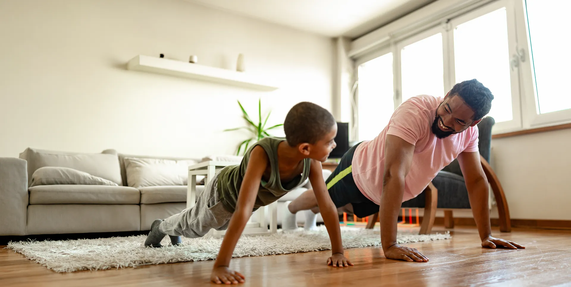 A father and his son doing press-ups together at home, keeping active as a family.